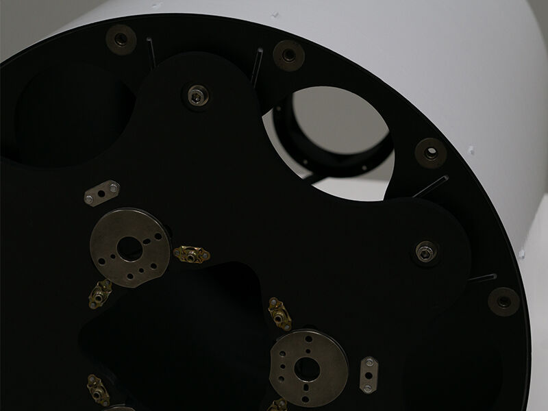 Satellite imaging optical metering structure. Image shows large white tube on its side. The closeup shows of details of the black carbon fiber side panel with metallic inserts.